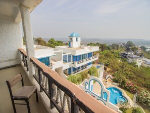A hotel with a pool, a view of the surrounding landscape, and a balcony with a chair. - OYO 11899 Home Greek Style 4BHK Penthouse Bambolim (Panaji)