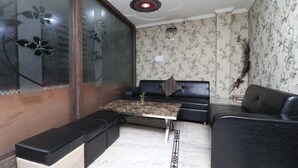 A modern living room with a glass partition, a sofa, a coffee table, and a patterned floor.