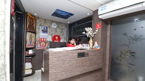 A reception desk with a wooden finish, a clock on the wall, and a vase with flowers.