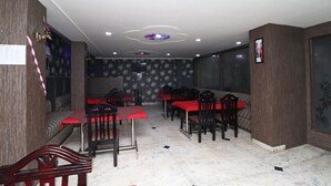 A restaurant with multiple tables and chairs, a patterned wall, and a ceiling with recessed lighting.