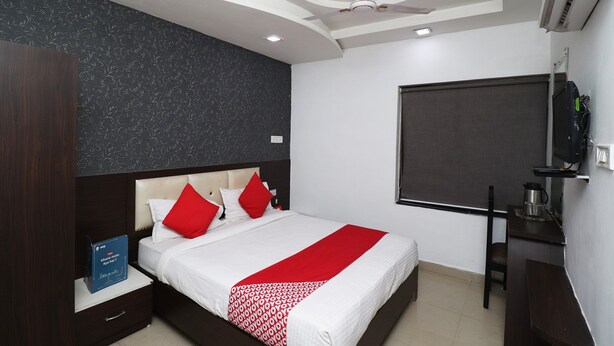 A hotel room with a bed, a desk, a chair, a wardrobe, and a television.