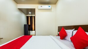 A hotel room with a bed, red and white bedding, a red throw, and a ceiling air conditioner. - OYO 11929 Hotel Ridhi Sidhi (Indore)