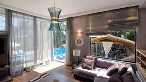 Ein geräumiges Wohnzimmer mit großem Fenster, einer Couch, einem Couchtisch und einem Kamin.