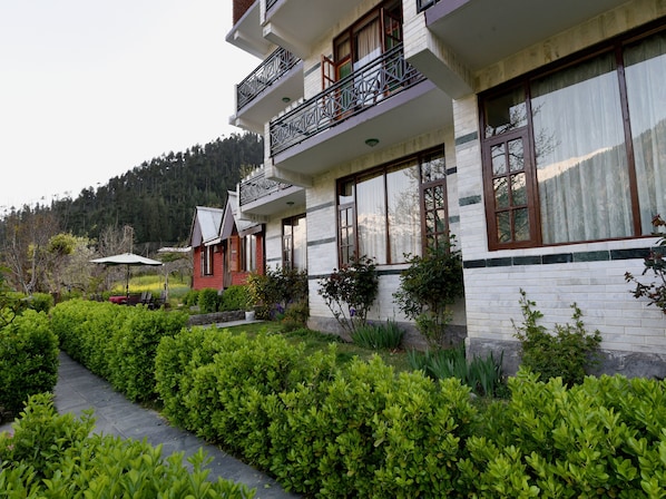 A two-story building with a balcony, surrounded by well-maintained greenery and a pathway.