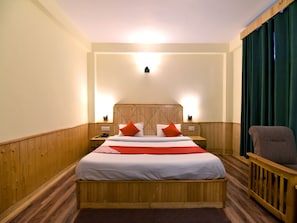 A hotel room with a wooden bed, two bedside tables, a chair, and a large window with curtains.
