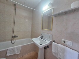Un baño con bañera, lavabo, ducha y espejo.