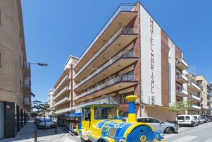 Un hotel de varios pisos con balcones y un tren en la calle.
