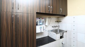 A kitchen with wooden cabinets, a sink, and a water dispenser. - OYO 12437 Home Valley View 2BHK Villa Gun Hill (Dehradun)