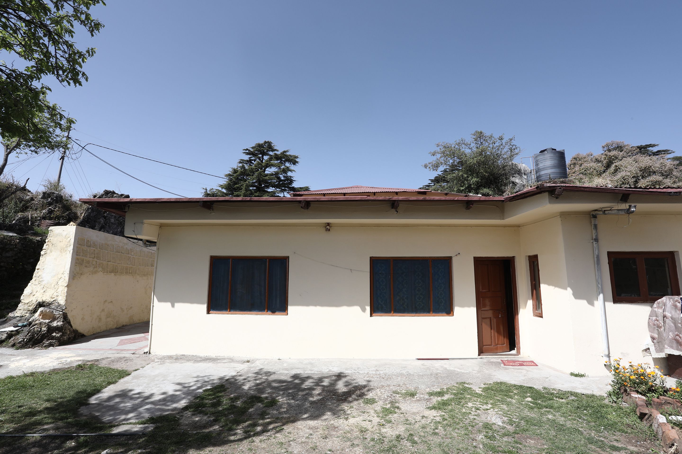 A single-story house with a red-tiled roof, two windows with wooden frames, and a door.