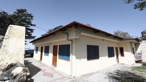 A two-story house with a tiled patio, a wooden door, and a stone wall. - OYO 12437 Home Valley View 2BHK Villa Gun Hill (Dehradun)