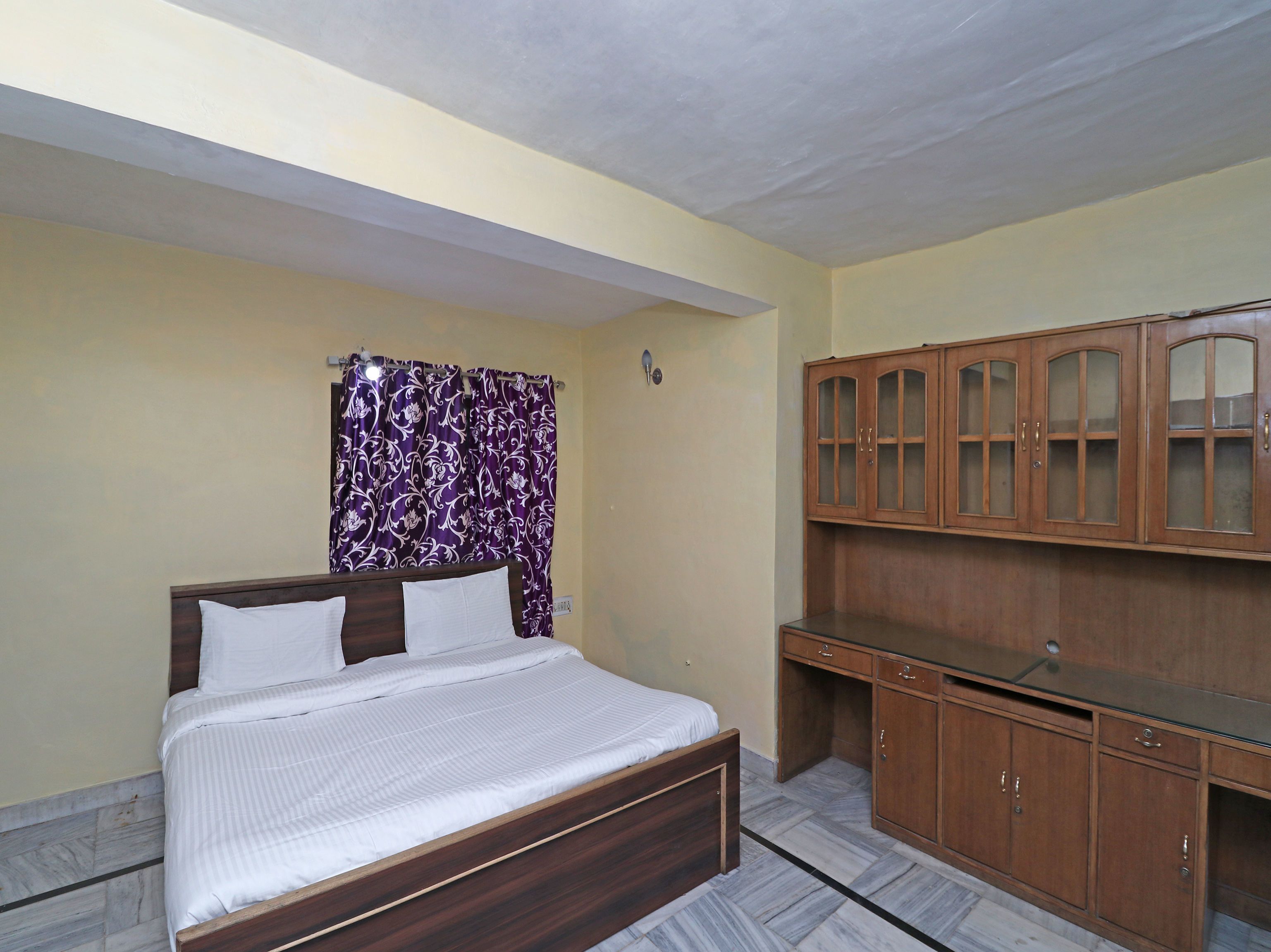 A bedroom with a bed, a desk, and a wardrobe.