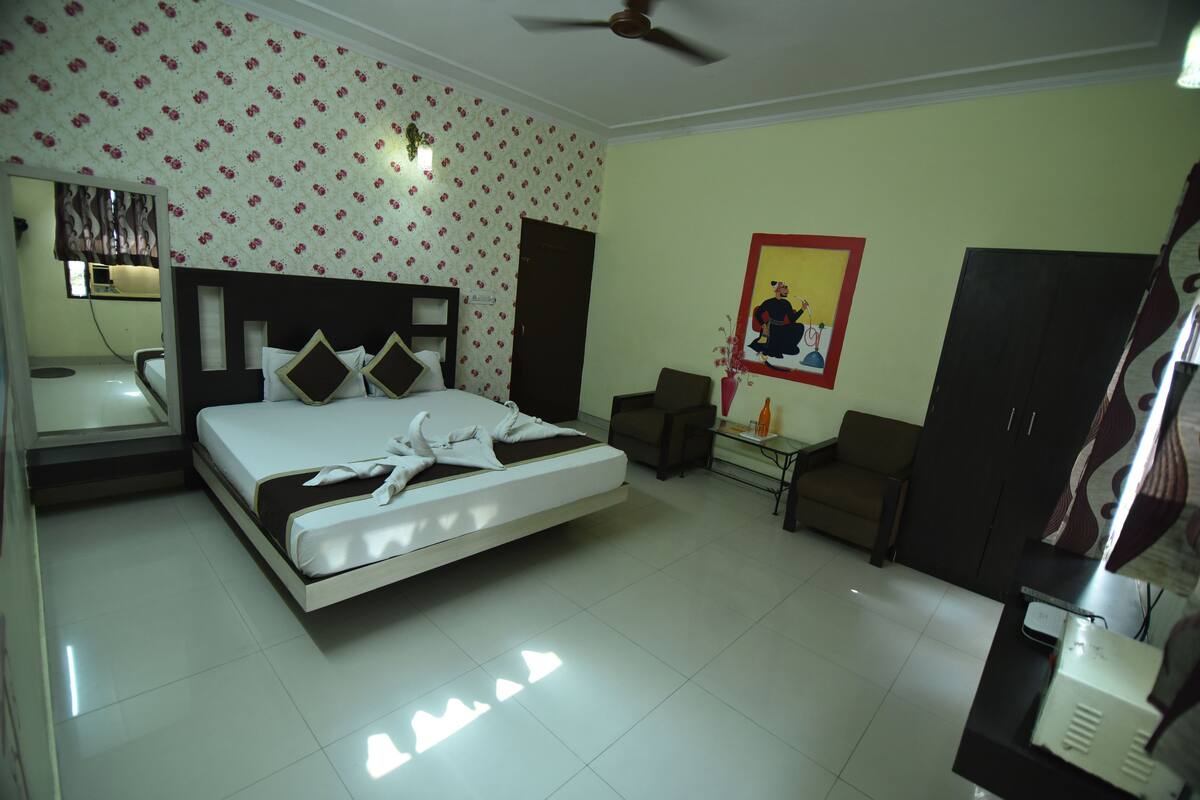 A hotel room with a bed, a desk, a chair, a wardrobe, and a ceiling fan.