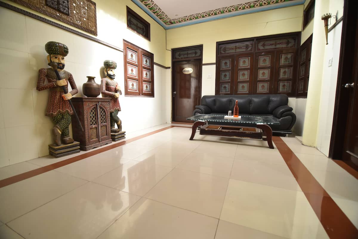 A room with a black leather sofa, a wooden cabinet with decorative items, and a tiled floor.