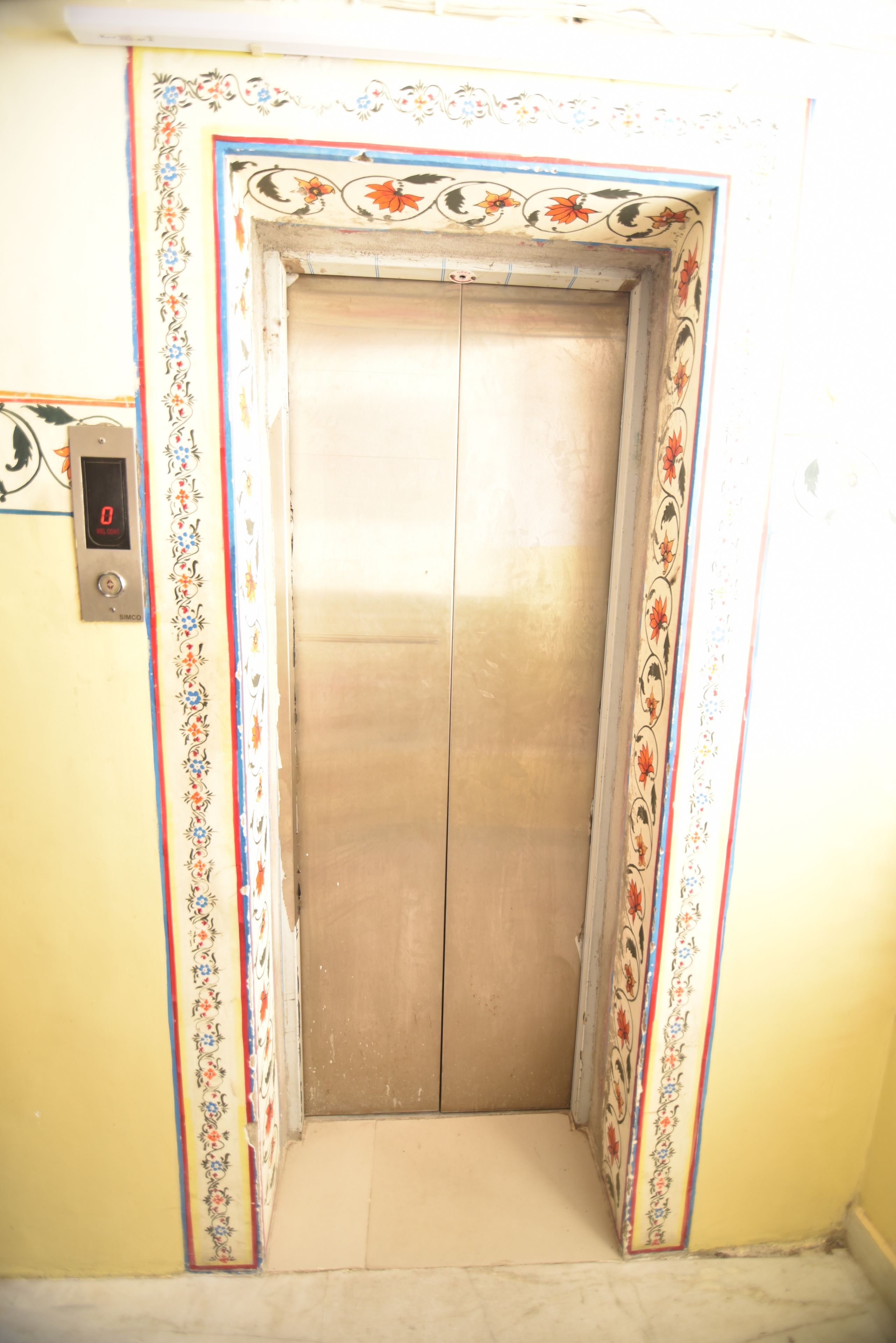 An elevator with floral patterns on the walls and a digital display on the left.