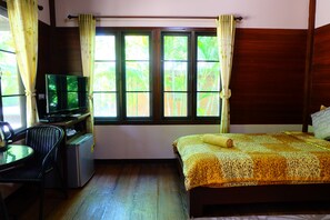 A room with a bed, a desk with a television, and a small refrigerator.