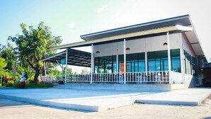 A modern building with a covered outdoor seating area, large windows, and a clear sky. - Phutien Resort (Chiang Rai)