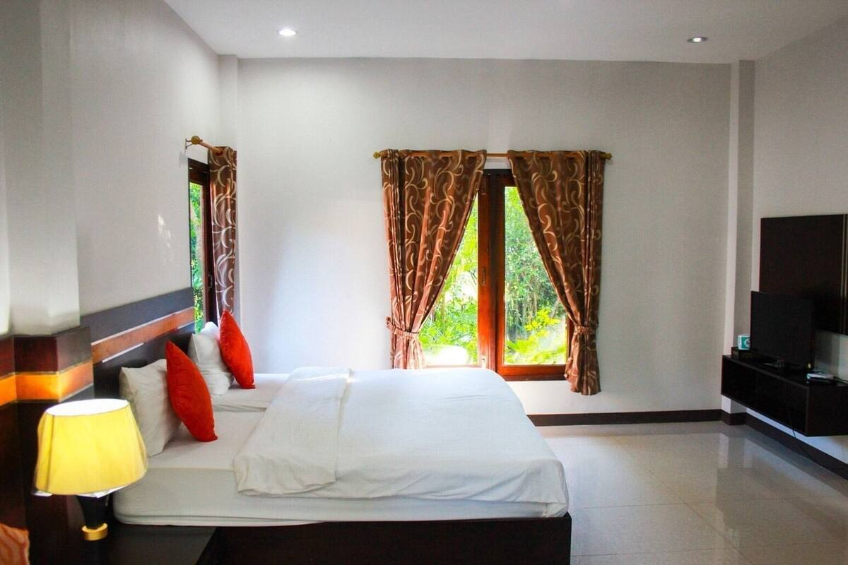 A hotel room with a large bed, a TV, and curtains on the windows.