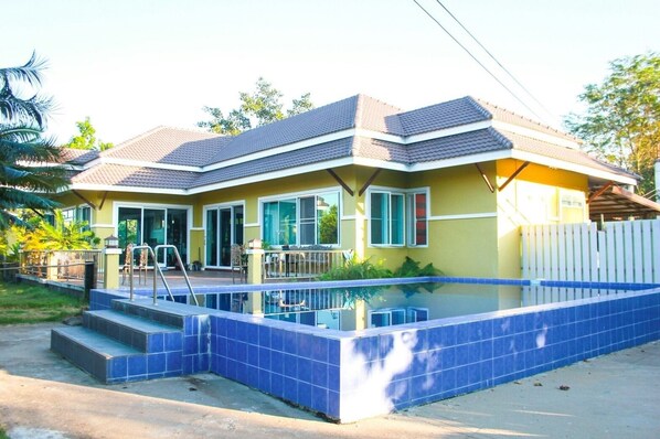 A two-story house with a swimming pool, a covered patio, and a fenced yard.