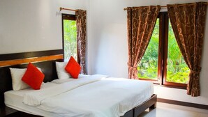 A hotel room with a large bed, two windows with curtains, and a view of greenery outside. - Phutien Resort (Chiang Rai)