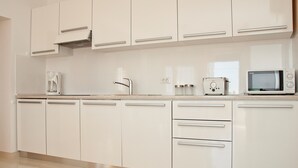 Eine moderne Küche mit weißen Schränken, einer Kaffeemaschine, einem Toaster und einer Mikrowelle.