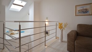 Ein modernes Interieur mit einer Metallreling, einer weißen Vase mit Blumen und einem gerahmten Bild an der Wand.