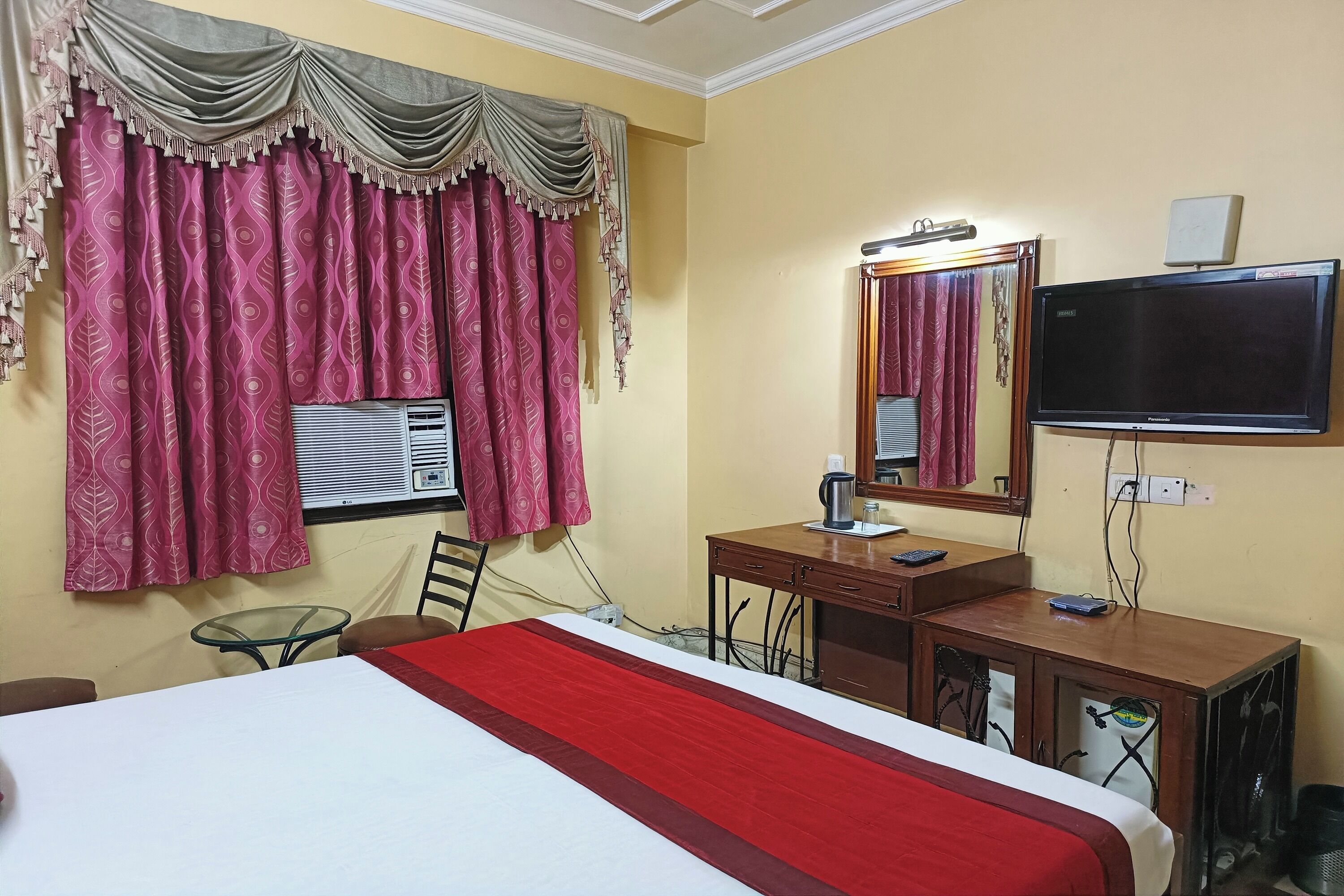 A hotel room with a bed, a desk, a television, and a mirror.