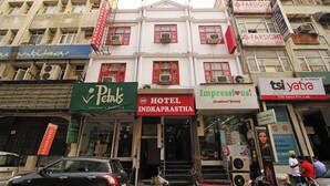 A hotel with a red and white facade, multiple air conditioning units, and a sign for 'Impressions!' advertising a 'Complimentary Youth Hostel'. - Hotel Indraprastha (New Delhi)