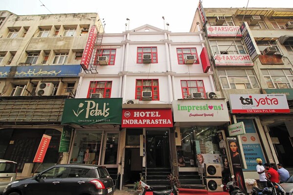 A hotel with a red and white facade, multiple air conditioning units, and a sign for 'Impressions!' advertising a 'Complimentary Youth Hostel'.