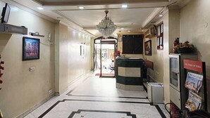 A hotel corridor with a reception desk, a chandelier, and a Times of India newspaper stand. - Hotel Indraprastha (New Delhi)