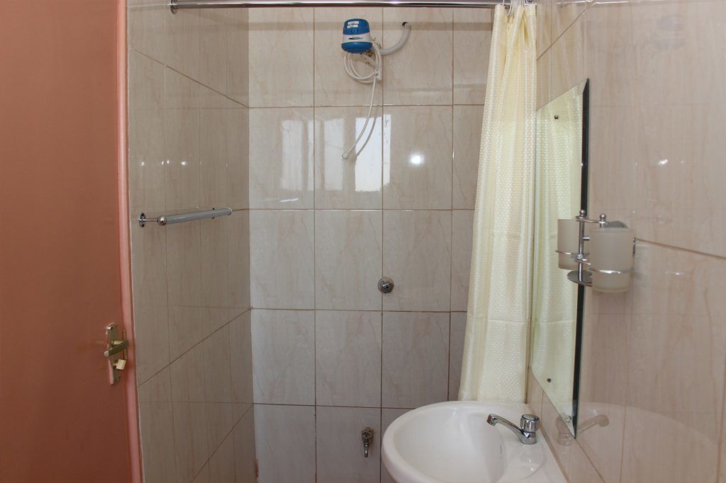 Une salle de bain avec une douche à parois de verre, un lavabo, un miroir et un porte-serviettes.