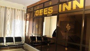 A hotel reception area with a GEES INN sign, a reception desk, and a waiting area with chairs. - Gees Inn (Nakuru)