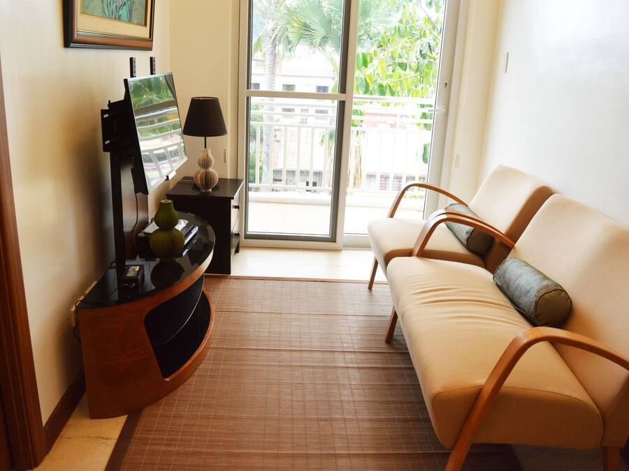 A living room with a sofa, a small table with a lamp, and a painting on the wall.
