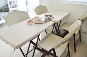 Una habitación pequeña y moderna con una mesa blanca y dos sillas. Hay libros sobre la mesa.