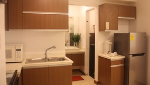 A compact kitchen with a microwave, sink, and refrigerator. - Centtro Residences (Los Banos)