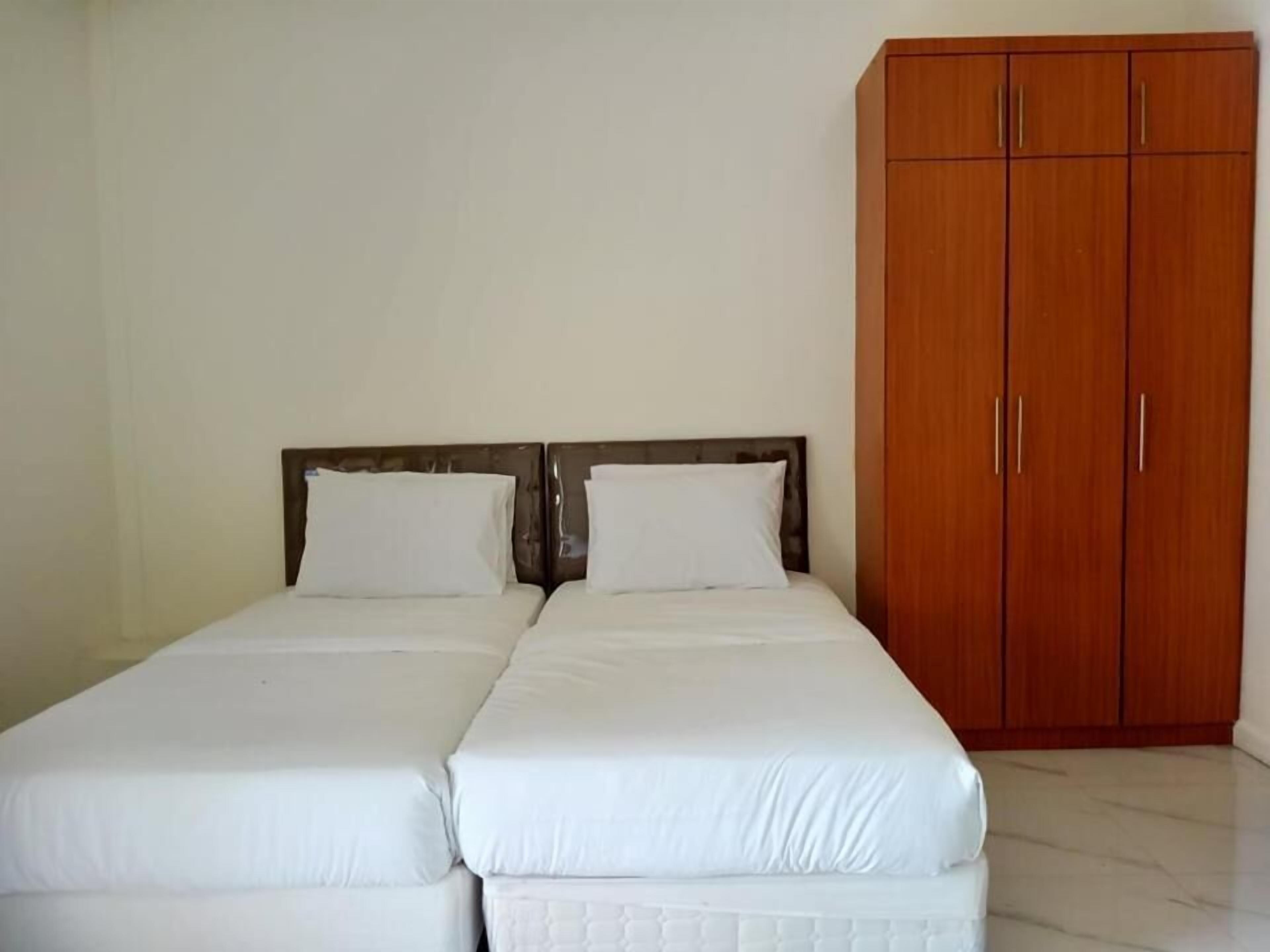 Una cama doble con ropa de cama blanca y un armario de madera con dos puertas.