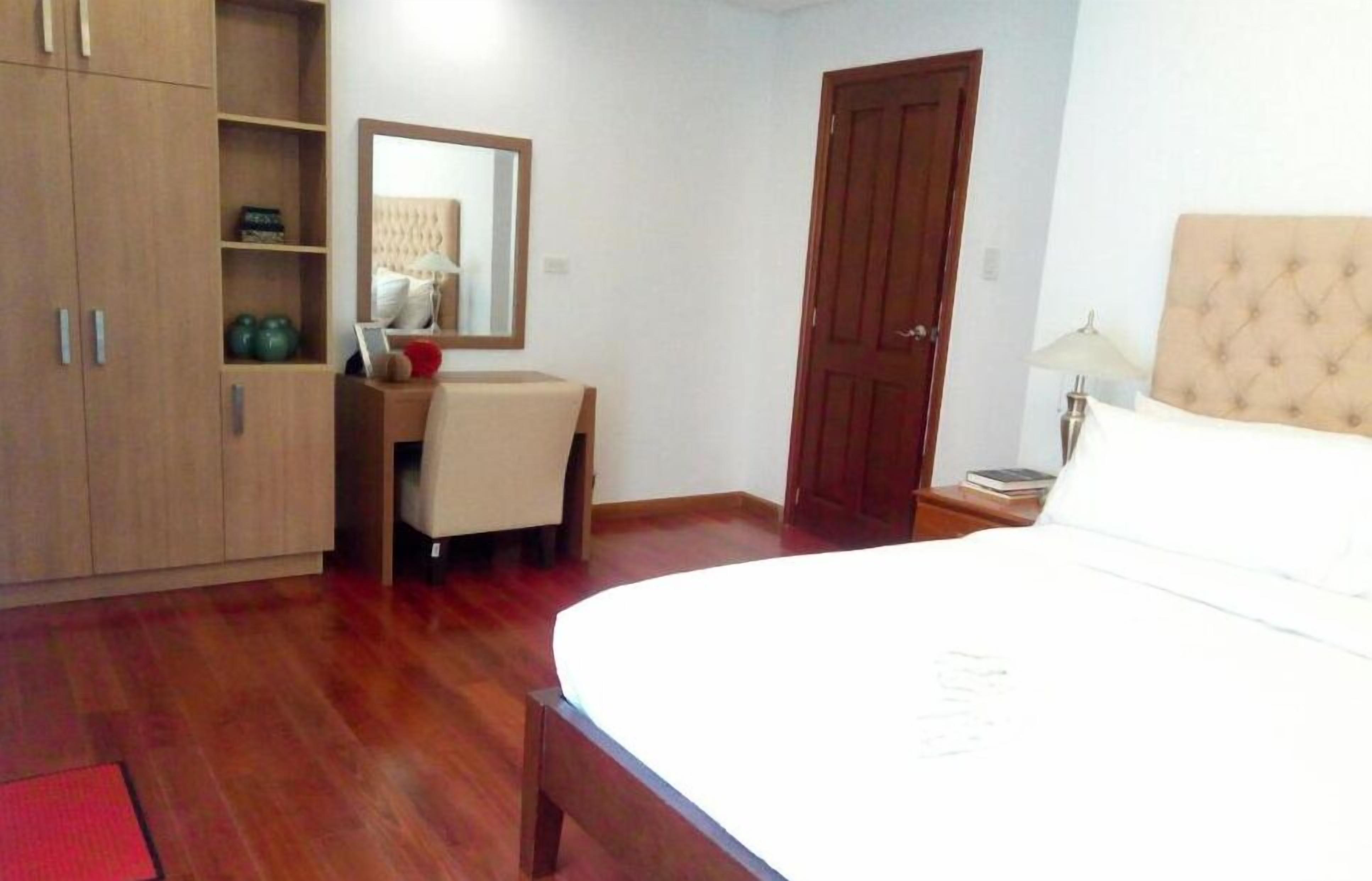 A bedroom with a bed, a desk, a wardrobe, and a door.