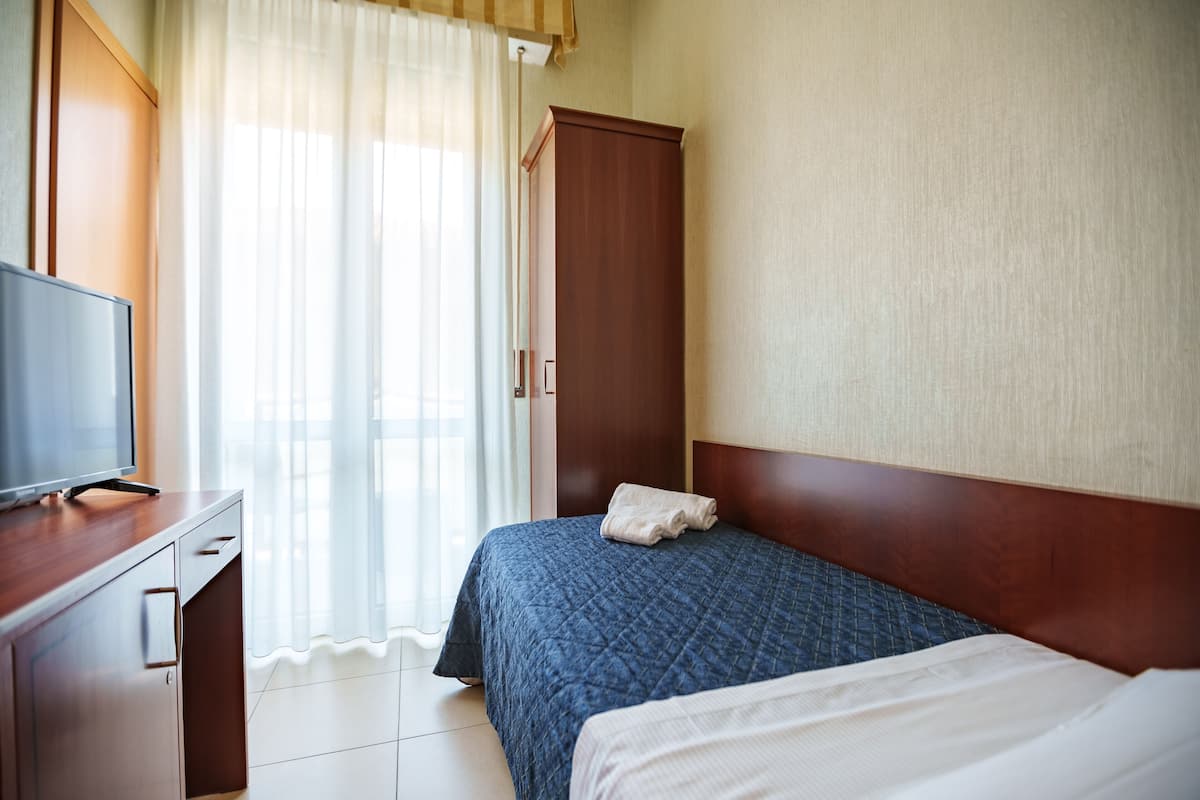 Una habitación de hotel con una cama, un televisor sobre una cómoda de madera y un armario.