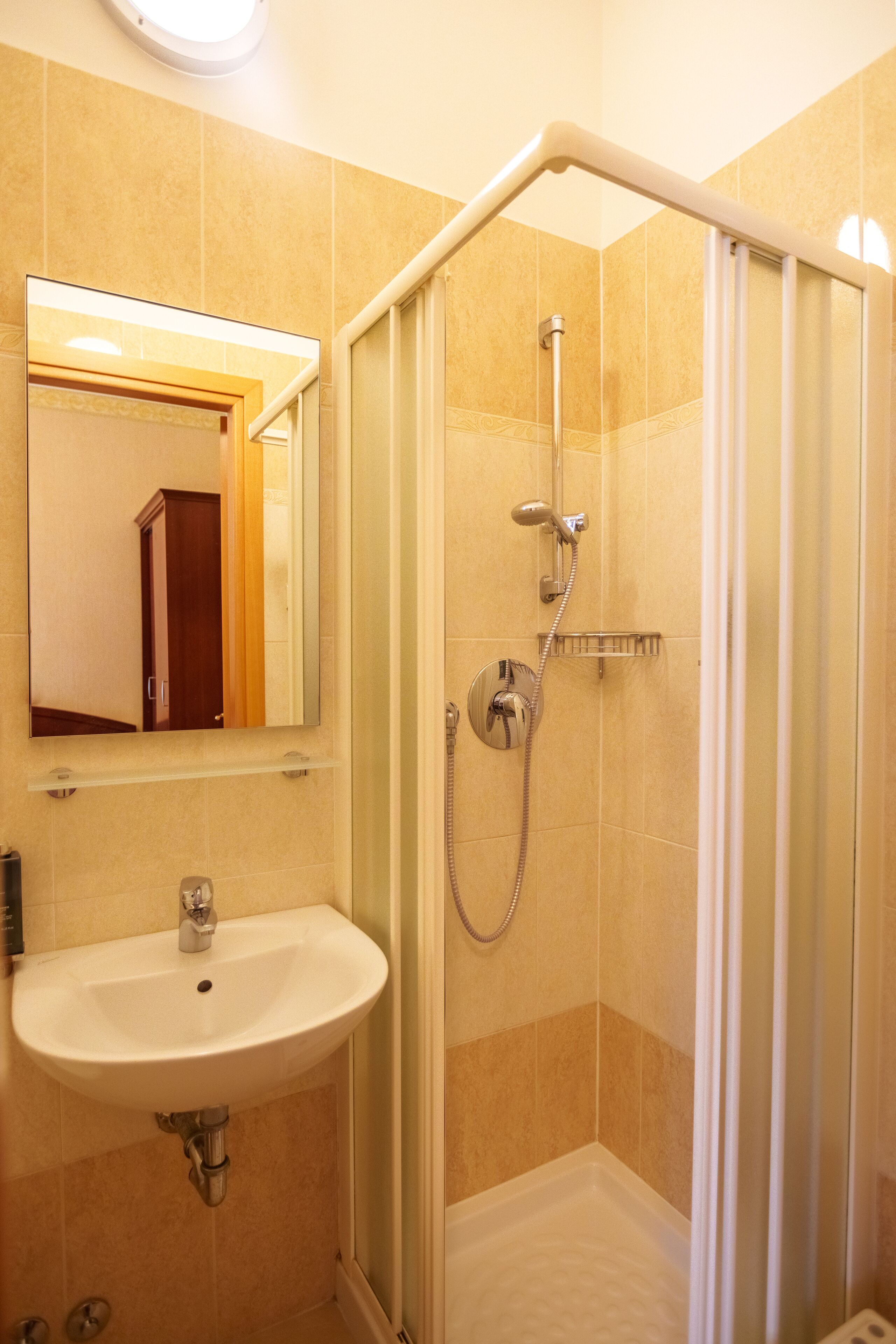 Een badkamer met een douchecabine, een wastafel en een spiegel.