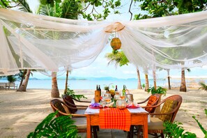 A beachside dining setup with a table, chairs, and a view of the sea. - Bamboo Private Islands (Culion Island)
