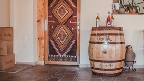 A wooden door with a geometric patterned design, a large wooden barrel with the word "Army" on it, and a potted plant on a shelf. - Hotel Mirhav (Goris)