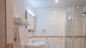 A bathroom with a glass shower enclosure, a sink, and a toilet.