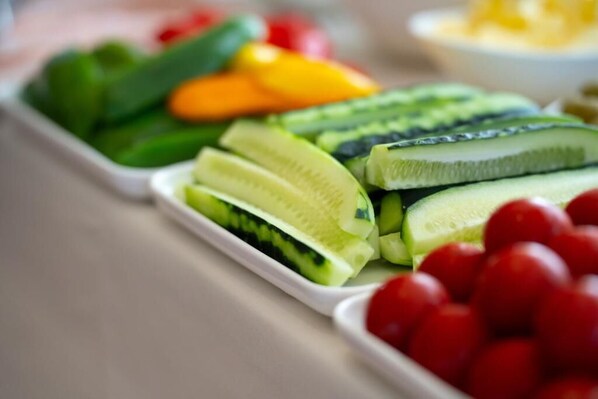A tray of sliced fruits including kiwi, cherry tomatoes, and bell peppers.