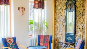 A room with two rocking chairs, a small table, and a stone wall.