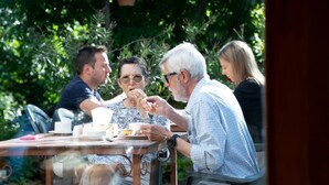 A group of people dining at an outdoor table with chairs and a glass partition. - Hotel Mirhav (Goris)