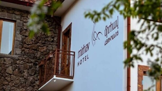 A building with a stone facade and a white wall with the text "Mirav Hotel".