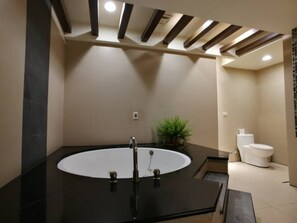 Une salle de bain moderne avec un lavabo noir, des toilettes blanches et une plante en pot.