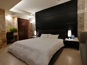 Une chambre d’hôtel moderne, dotée d’un grand lit, d’un bureau et d’une chaise.