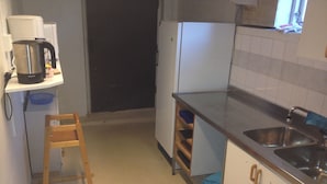 Een kleine keuken met een koffiezetapparaat, een koelkast en een spoelbak.