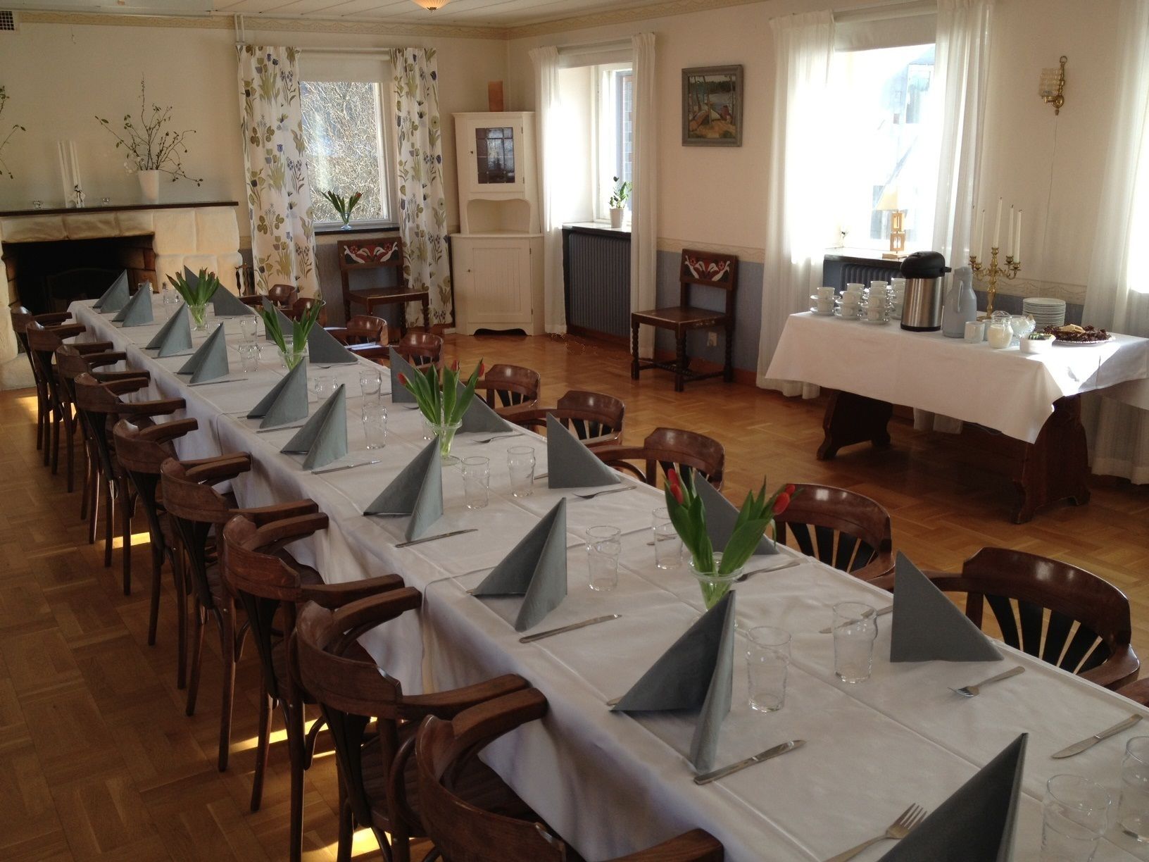 A dining area with a long table set for a meal, surrounded by wooden chairs.