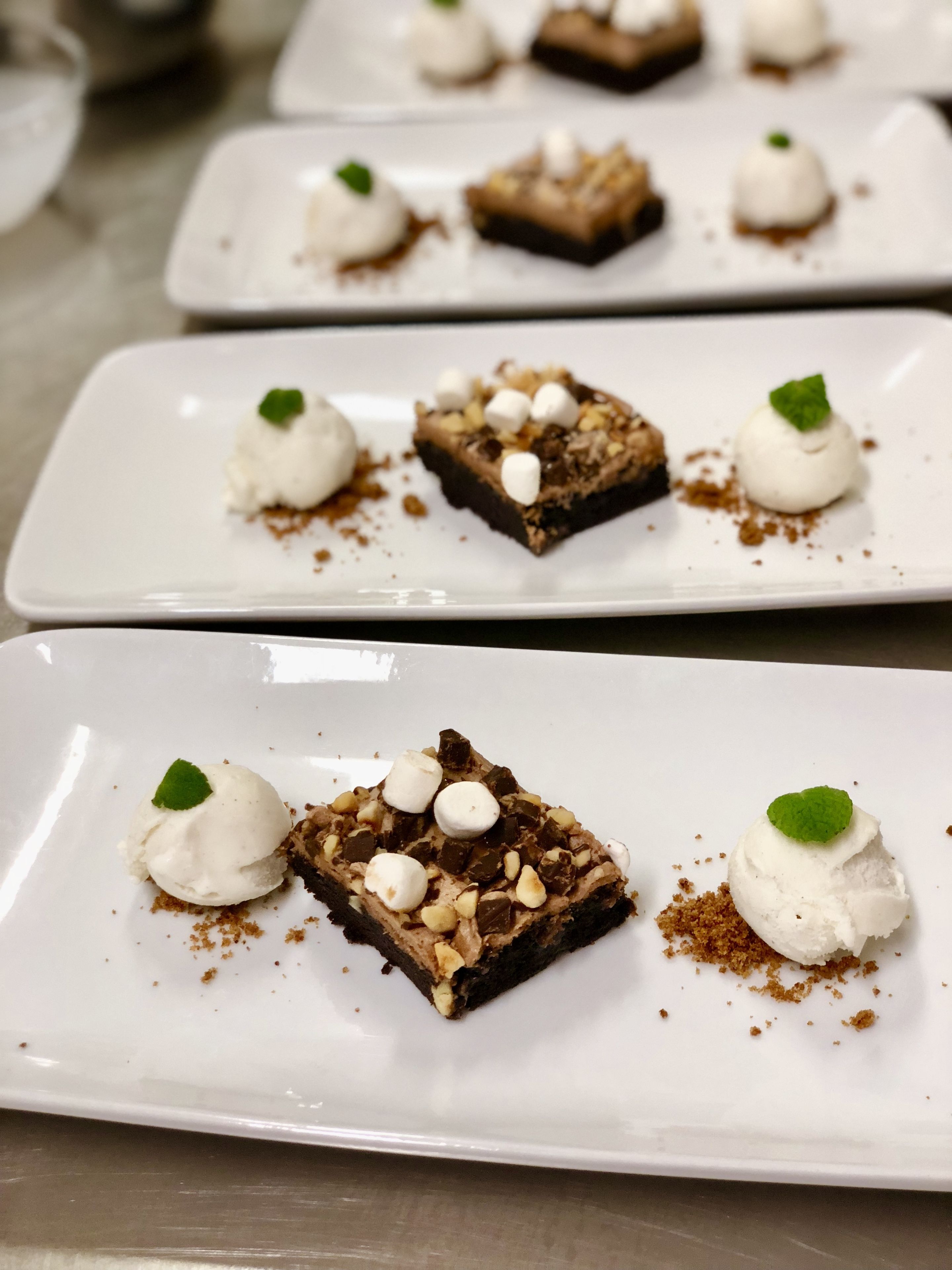 A dessert plate with a brownie, marshmallows, and a scoop of ice cream.